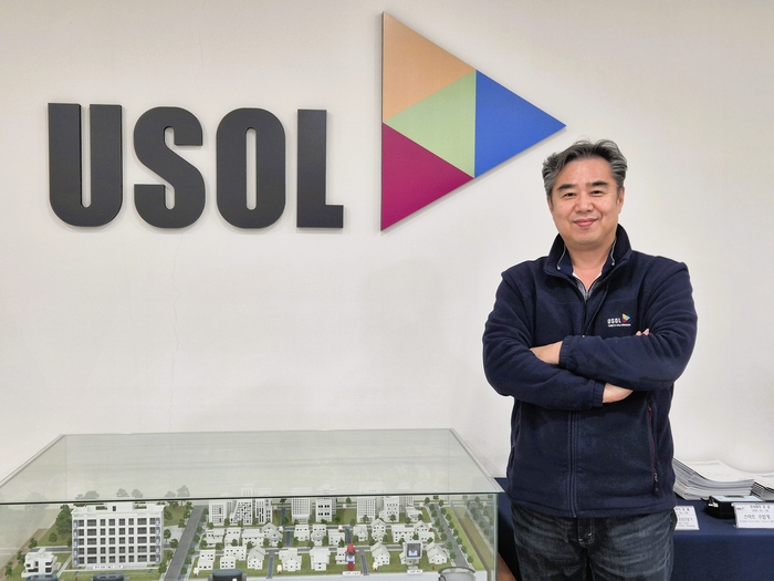 오광석 <주>유솔 대표가 자사 브랜드 로고 앞에서 포즈를 취하고 있다. 이승엽기자