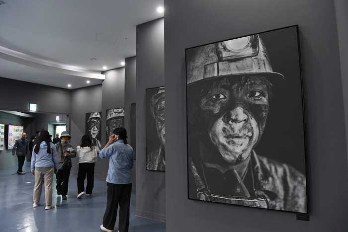 문경석탄박물관 전시관 내부에서 관람객들이 광부의 삶을 담은 대형 흑백 사진 작품을 살펴보고 있다. <강남진 기자>