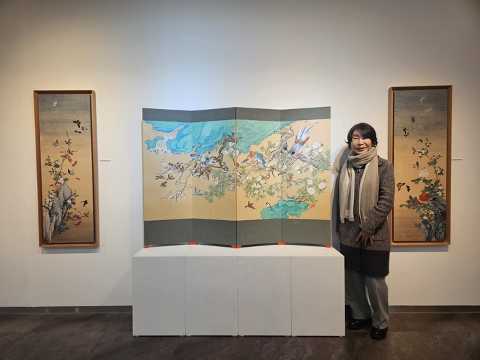 권정순 작가가 대덕문화전당 신춘특별 기획전시 권정순·박세호 초청 MAESTRO전에서 새롭게 선보이는 교태전 부벽화 화조도 옆에서 포즈를 취하고 있다. 권혁준기자 hyeokjun@yeongnam.com