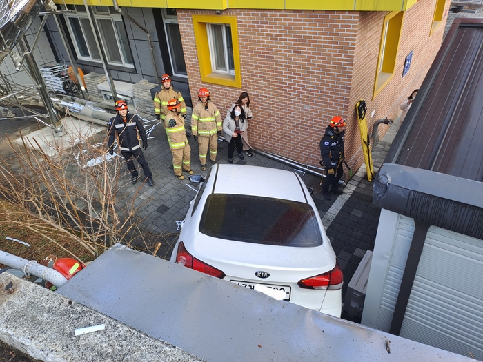 6일 오후 경북 문경시 점촌로 문경유치원 인근 도로에서 승용차가 도로 아래 유치원 건물 인근으로 추락하는 사고가 발생한 가운데, 출동한 소방대원들이 현장에서 사고 차량 주변을 확인하며 안전 조치를 하고 있다. <강남진 기자>