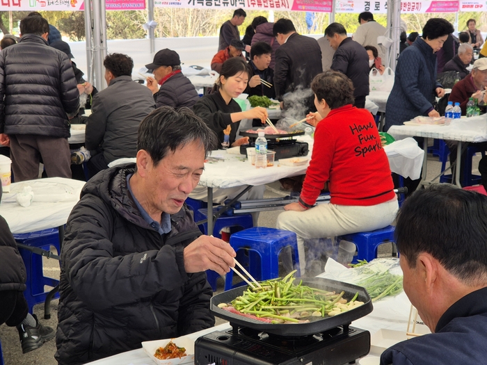지난 13일 미삼 직거래 장터 내 마련된 미삼 체험장에서 한 시민이 미나리와 삼겹살을 불판에 올려놓고 구우면서 환하게 웃고 있다. 이승엽기자
