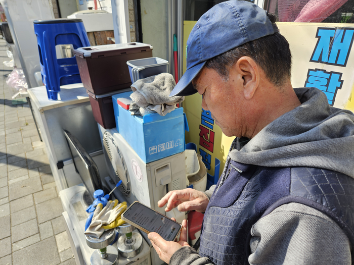 대구 남구 대명동에서 재활용부터 마카다를 운영하는 윤부현 대표가 스마트폰을 통해 중고거래 플랫폼을 확인하고 있다. 정지윤기자 yooni@yeongnam.com