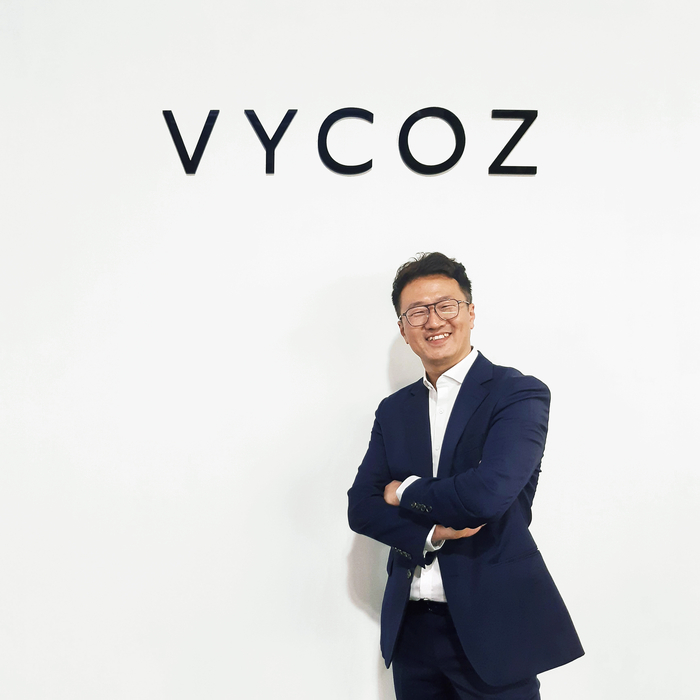 <주>정스옵티칼 정병재 대표가 자사 브랜드 앞에서 포즈를 취하고 있다. <정스옵티칼 제공>