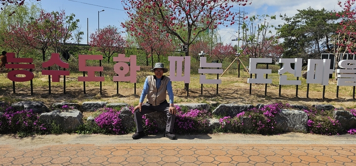 박돈헌 이장이 마을 입구에 앉아 기념사진을 찍고 있다. <석현철 기자>