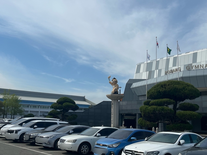 포항종합운동장 주차장 인근에 외롭게 서 있는 올림픽성화봉송기념탑(일명 호돌이탑). 탑이 많은 시민들의 눈에 띄기 어려운 외진 곳에 설치돼 있어, 역사적 의미와 가치가 제대로 전달되지 못하고 있다는 지적이 이어지고 있다. 탑 주변으로 주차된 차량들이 가득하다.<김기태기자>