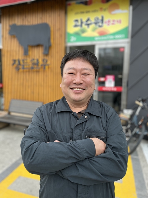 신동일 사장이 자신의 식당 앞에서 활짝 웃어 보이며 포즈를 취하고 있다.<김기태기자>