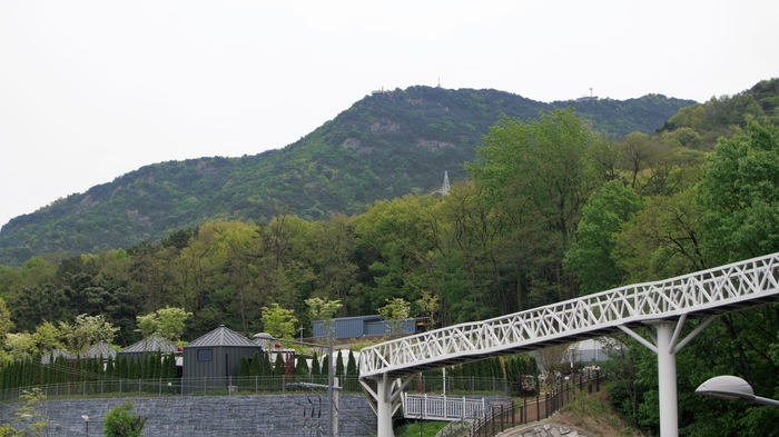 전망대에서 하늘다리를 건너면 숲속 책 쉼터와 앞산자락 길로 연결된다. 앞산 봉우리에 전망대가 조그맣게 보인다.