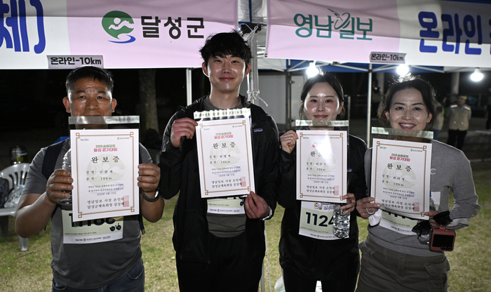 25일 대구 달성군 옥연지 송해공원 일원에서 열린 2026 송해공원 달성 걷기대회에 참가한 시민들이 코스를 완주한 뒤 완보증을 들어 보이며 환하게 웃고 있다. 이윤호기자 yoonhohi@yeongnam.com