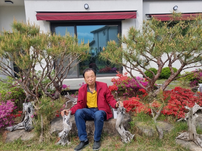 이종우씨가 소나무 뿌리로 만든 조각작품 옆에서 포즈를 취하고 있다.