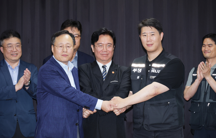 20일 경기도 수원시 장안구 경기고용노동청에서 열린 삼성전자 임금협상을 마친 후 여명구 삼성전자 DS(디바이스솔루션·반도체 사업 담당) 피플팀장과 최승호 삼성그룹 초기업노동조합 삼성전자지부 위원장이 잠정 합의안에 서명한 후 김영환 고용노동부 장관과 손을 맞잡고 있다.  연합뉴스
