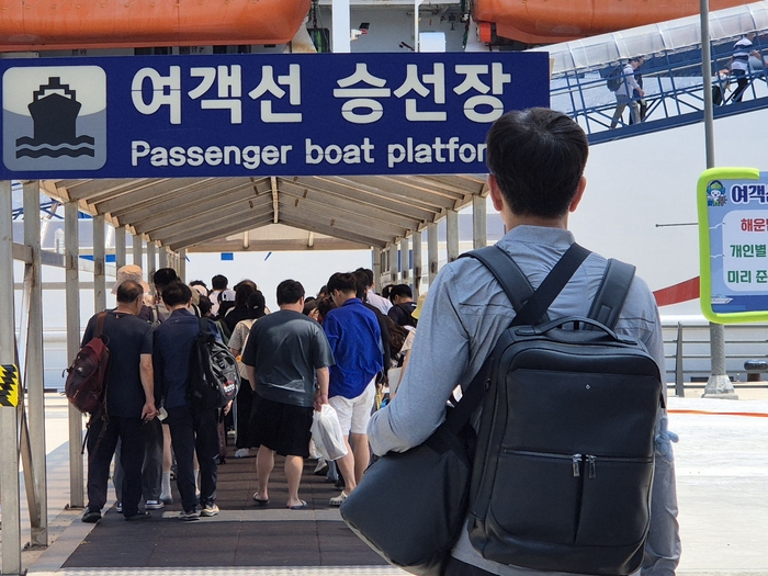 지난 17일 관광객들과 청년들이 사동항 승선장에서 육지로 나가기 위해 여객선에 오르고 있다. <홍준기 기자>
