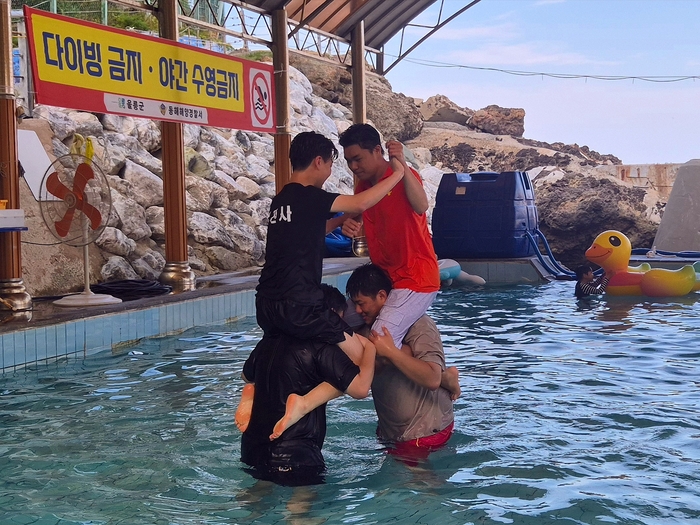 25일 울릉군 내수전 해수욕장에서 학생들이 어깨를 맞잡고 균형 잡는 게임을 하며 한여름의 더위를 잊고 있다. <홍준기 기자>