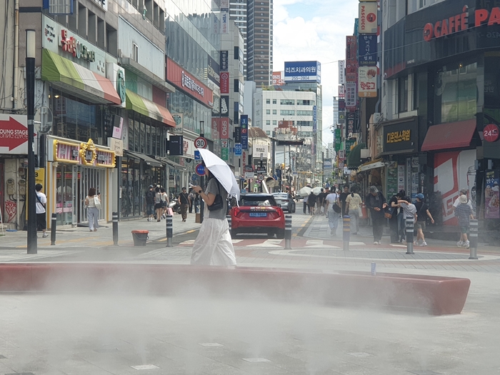 폭염중대경보가 내려진 26일 오후 대구 중구 동성로 일대에서 양산을 쓴 한 시민이  쿨링포그가 뿜어내는 물안개를 맞으며 지나가고 있다. 김민진 수습기자