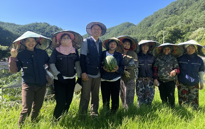 박상철 봉화군 법전면 소천1리 이장(왼쪽 세번째)이 외국인 계절근로자 사업을 통해 함께 일한 베트남 근로자들과 수박밭에서 수확한 수박을 들고 기념촬영을 하고 있다. <황준오기자>