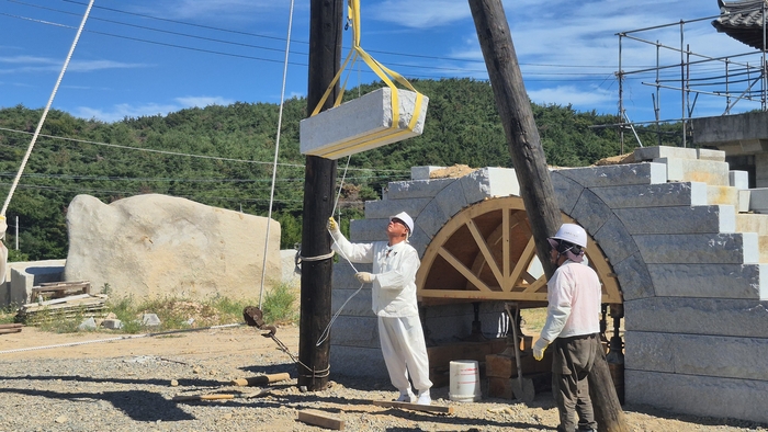 경주석장 윤만걸 선생과 전승자들이 지난 7일 경주시 통일로 시암공방에서 이맛대와 도르래를 이용해 약 1t의 석재를 들어 올린 뒤 홍예교 위 제자리로 옮기는 전통 드잡이 기술을 시연하고 있다. <장성재기자>