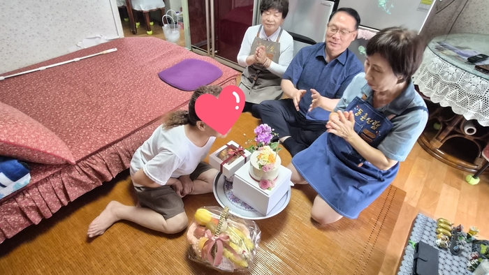 정미자(오른쪽 첫째)씨가 독거 어르신께 생일상을 전달하고 봉사자들과 함께 축하 노래를 부르고 있다. <정미자씨 제공>