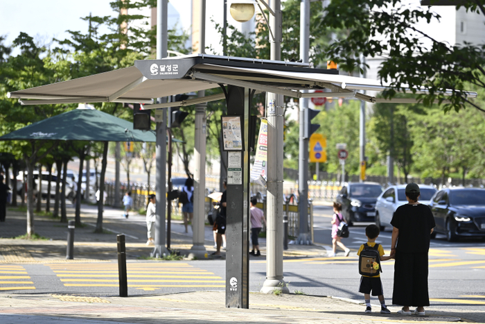 대구 달성군 유가초등학교 인근에 설치된 스마트 그늘막 아래에서 시민들이 햇볕을 피하고 있다. <달성군 제공>
