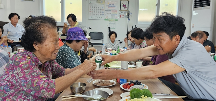 14일 포1리 마을회관에서 말복을 맞아 마을주민들이 함께 점심을 먹고 있다. 김정훈 이장이 마을 어르신에게 음료수를 부어주고 있다. 석현철 기자
