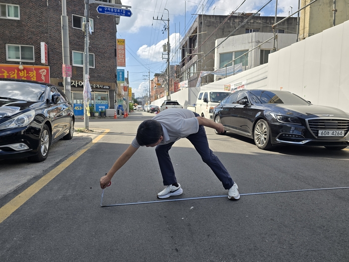이수욱 새마을중앙시장 상인연합회 회장이 시장 진입로 도로 폭을 줄자로 확인하고 있다.  박용기 기자