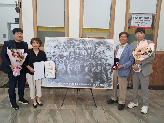 2025년 충북 영동에서 열린 6·25전쟁 제75주년 기념식에 전시된 국군17연대 사진 앞에서 김규호씨가 부인, 두 아들과 함께 포즈를 취했다. 김규호씨 제공
