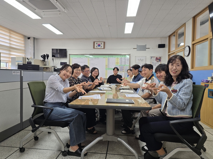 구미 옥성초 선생님들이 교무실 회의 테이블을 사이에 두고 옥성초 야호를 외치며 손동작을 만들고 있다. 박용기 기자