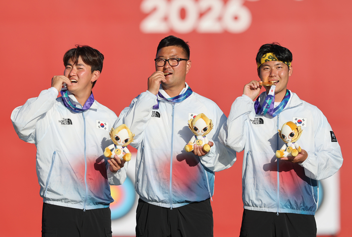 2일 일본 아이치현 오카자키 중앙종합공원 다목적광장에서 열린 2026 아이치·나고야 아시안게임 양궁 리커브 남자 단체전에서 금메달을 차지한  대한민국 김제덕(왼쪽부터), 김우진, 이우석이 메달을 깨물어보고 있다. 연합뉴스