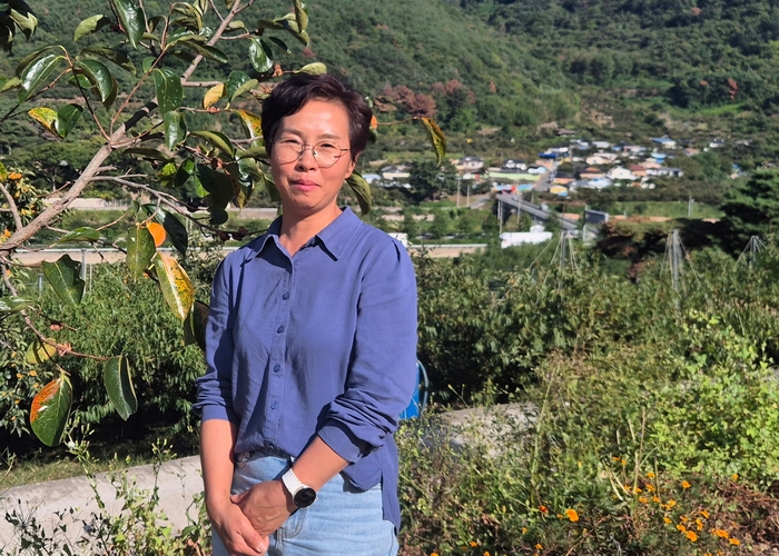 정은영 이장이 자신의 스마트팜 농장에서 월곡2리 마을을 배경으로 사진을 찍고 있다. 박성우 기자