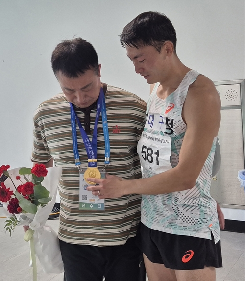 지난 19일 제주 강창학종합경기장에서 열린 전국체전 남자 일반부 400m 허들 경기에서 우승을 차지한 대구의 김주호가 자신의 스승인 권혁찬 감독에게 금메달을 걸어주며 눈물을 흘리고 있다. 권 감독도 함께 눈시울을 붉혔다.