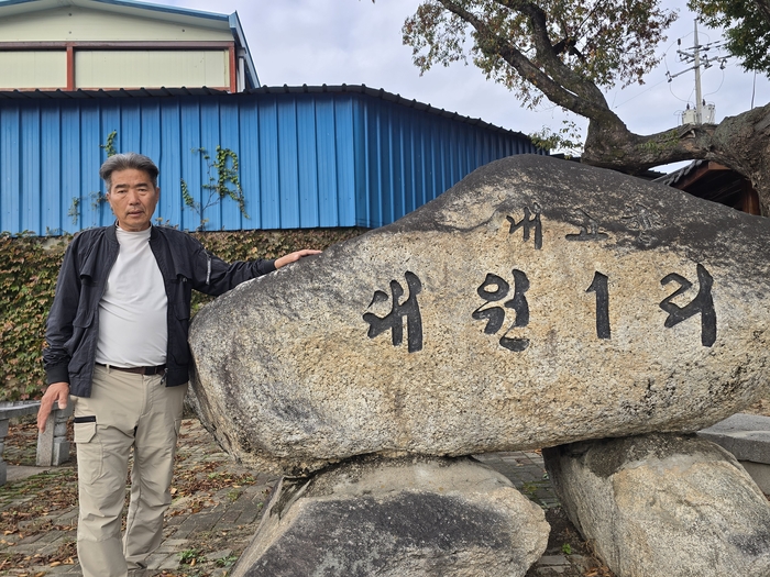 옥성면 대원1리 서정구 이장이 마을 표지석 앞에서 포즈를 취하고 있다. 박용기기자