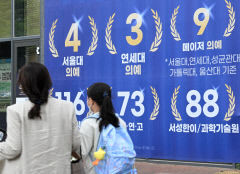 [포토뉴스] 의대 입시 홍보 현수막 앞으로 지나가는 시민들