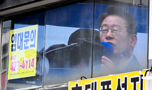 [포토뉴스] 상가 공실 유리창에 비친 이재명 후보